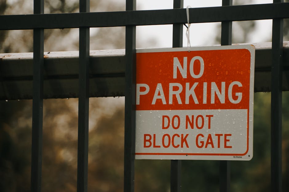 A close-up of a white reserved parking sign with green borders and text indicating parking for disabled individuals, featuring a blue wheelchair symbol. Below, an additional smaller sign specifies a maximum fine of $500 for violations. The signs are mounted on a metal post situated on a paved area adjacent to a property, with lush green trees and foliage in the background. The scene is set during daylight with natural lighting, and the signs are positioned in an outdoor environment consistent with urban or suburban parking regulations. As part of home relocation or furniture transport logistics, these signs are relevant for ensuring compliance with parking restrictions during removals, handled by Man and Van Hither Green.