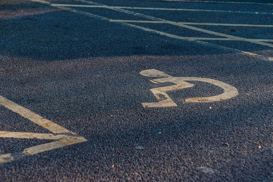 Close-up view of a designated parking space for removals vehicles, featuring faded white paint on dark asphalt pavement with a clearly marked number '12' enclosed in a circle, located near the entrance of a residential property in Hither Green. The surface shows slight wear and scattered small debris, with parking lines visible adjacent to the space. This setting is likely part of a home relocation process, where a van from Man and Van Hither Green is scheduled to load or unload furniture and packed boxes. The area is outdoors, with natural daylight casting soft shadows, and the environment suggests a typical village or suburban street in the Hither Green area, suitable for professional packing, loading, and furniture transport services.